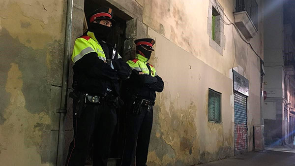 Dos mossos ante el portal de la calle de la Riera Alta donde se ha cometido el crimen. Foto: Guillem Sánchez | El Periódico mossos-raval